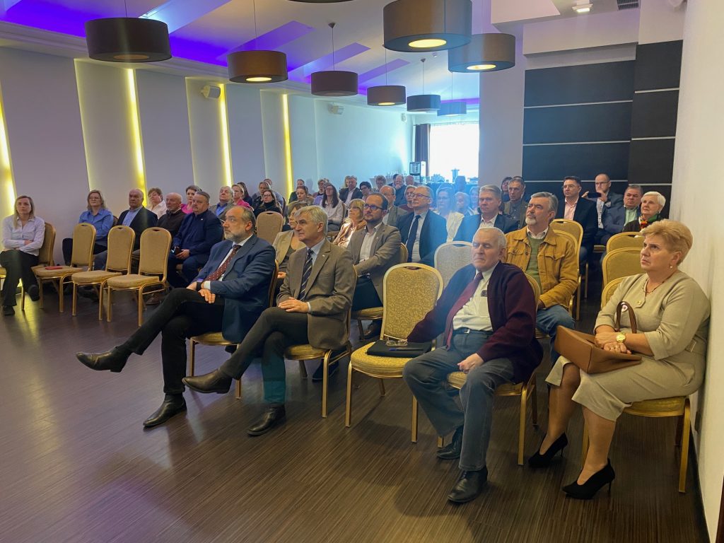 Zdjęcie przedstawia siedzących uczestników konferencji